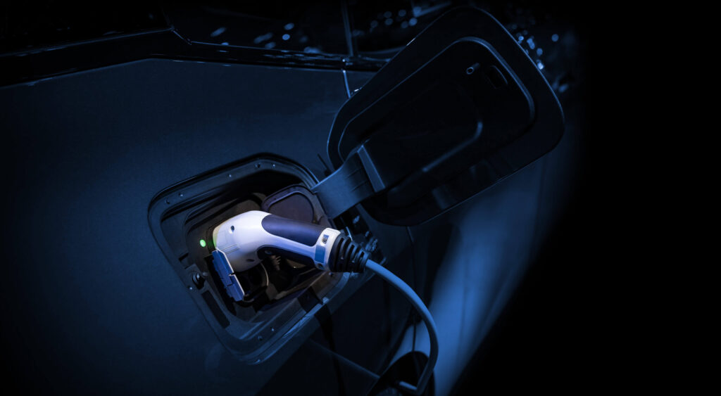 Economy 7: The image shows an electric or hybrid car being charged in the dark, presumably at night
